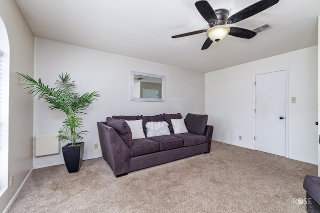 carpeted living room featuring ceiling fan and a textured ceiling