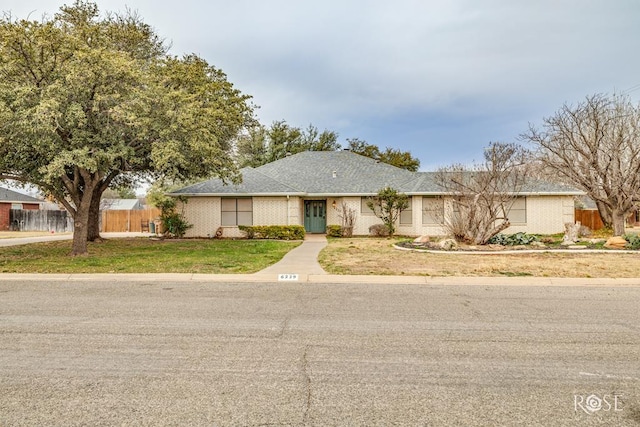 ranch-style house featuring fence and a front yard