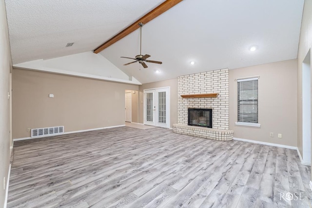 unfurnished living room with visible vents, a fireplace, light wood-style flooring, and beamed ceiling