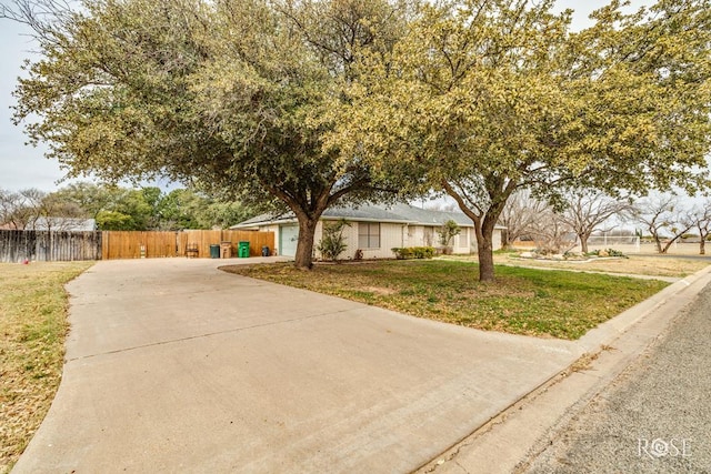 view of front of property featuring fence, a front lawn, and concrete driveway