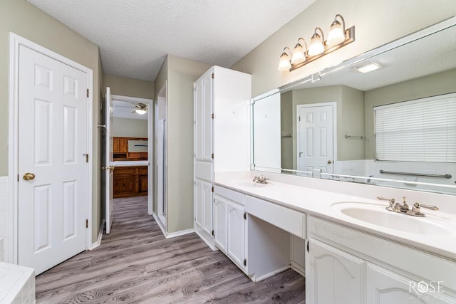 bathroom featuring a textured ceiling, double vanity, wood finished floors, and a sink