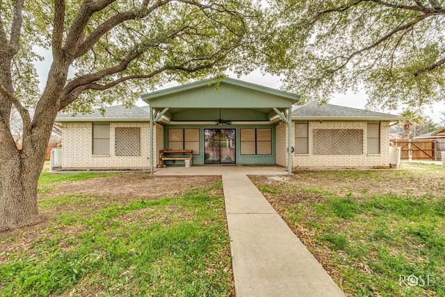 view of front of home with brick siding, a ceiling fan, a patio, fence, and a front yard