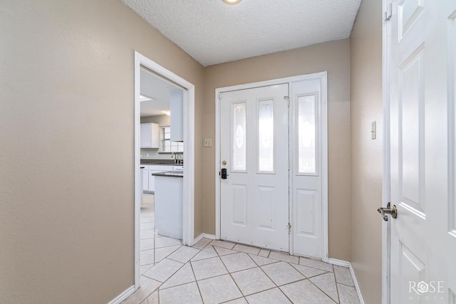 entrance foyer with a textured ceiling, light tile patterned flooring, and baseboards