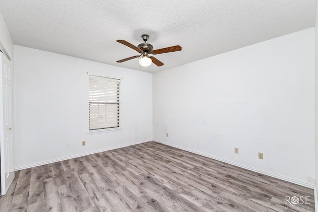 spare room featuring a textured ceiling, baseboards, a ceiling fan, and light wood-style floors