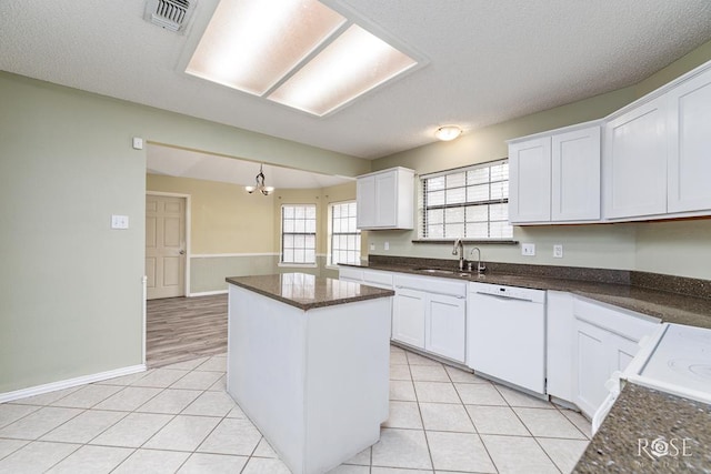 kitchen with light tile patterned floors, white cabinetry, a kitchen island, white dishwasher, and a sink