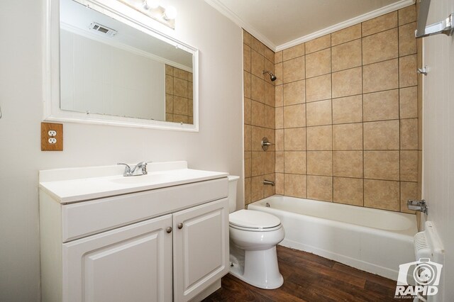 full bathroom featuring radiator heating unit, wood-type flooring, tiled shower / bath combo, toilet, and crown molding