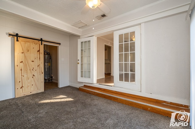 unfurnished room with a barn door, carpet flooring, water heater, and a textured ceiling