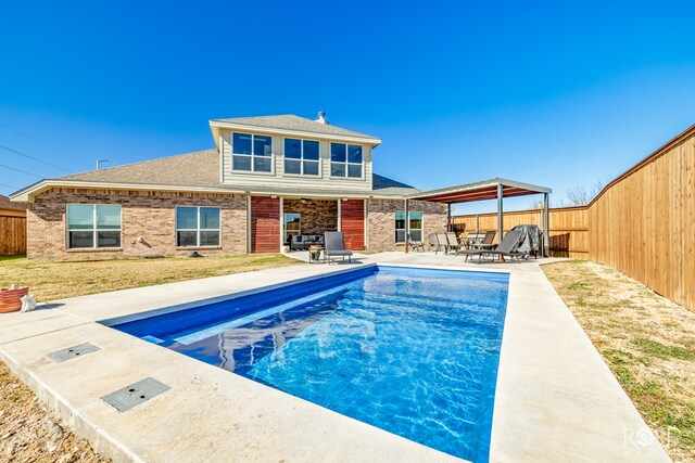 rear view of property with a fenced in pool, a gazebo, and a patio area