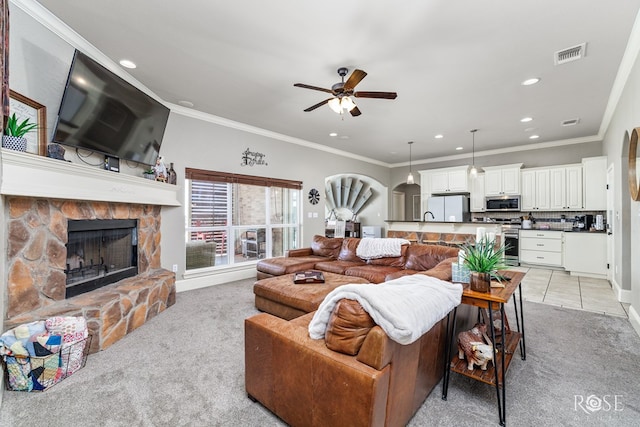 tiled living room with ceiling fan, ornamental molding, and a fireplace