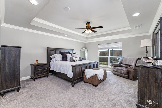 carpeted bedroom with a raised ceiling, ornamental molding, and ceiling fan