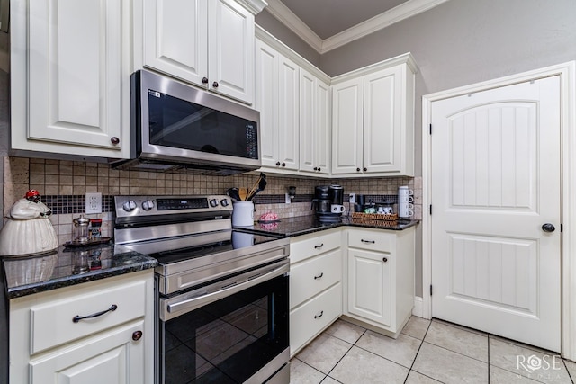 kitchen with white cabinetry, crown molding, light tile patterned floors, appliances with stainless steel finishes, and dark stone counters