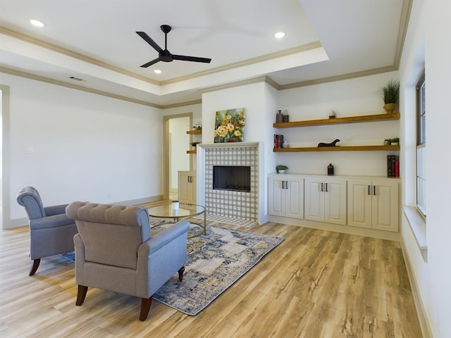3608 Clearview Dr, San Angelo, TX 76904 - living room with a raised ceiling, a ceiling fan, light wood-style flooring, a fireplace, and ornamental molding