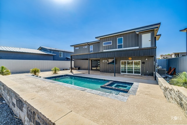 4992 Silver Creek Pass, San Angelo, TX 76904 - back of house featuring board and batten siding, a patio, a fenced backyard, and a pool with connected hot tub