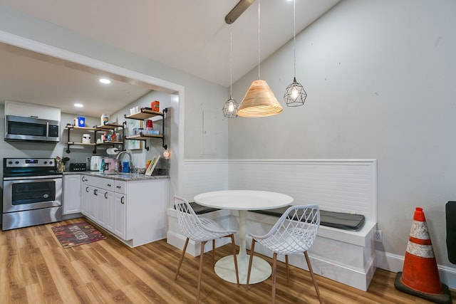 kitchen featuring pendant lighting, sink, white cabinetry, stainless steel appliances, and light wood-type flooring