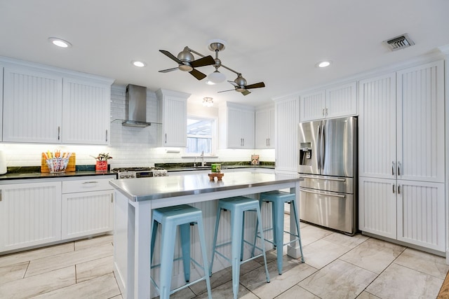 kitchen featuring white cabinetry, stainless steel fridge, a center island, range, and wall chimney exhaust hood