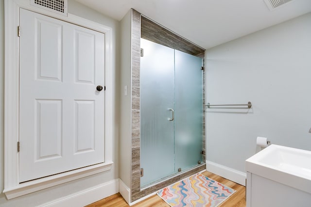 bathroom with hardwood / wood-style flooring and an enclosed shower