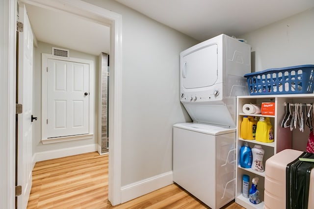 clothes washing area featuring wood-type flooring and stacked washing maching and dryer