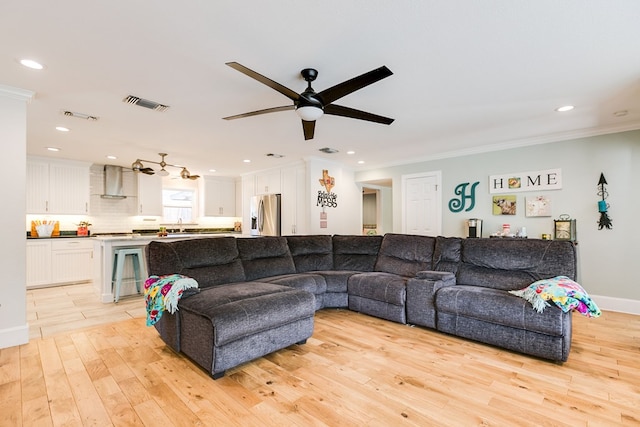 living room featuring ceiling fan, ornamental molding, sink, and light hardwood / wood-style flooring