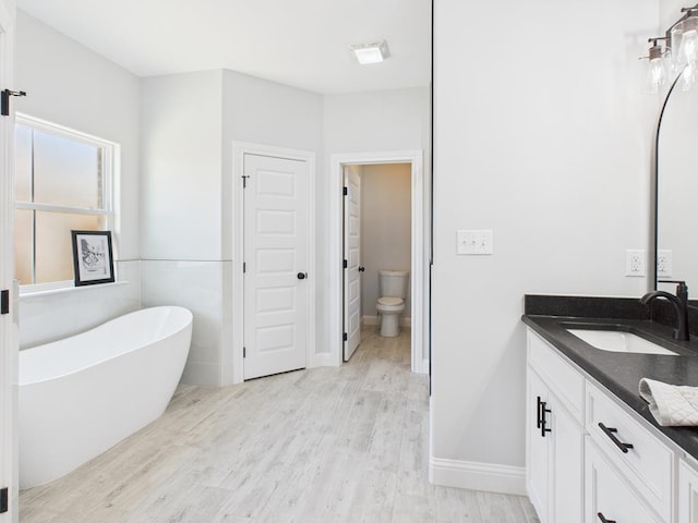 3725 Silver Spur Dr, San Angelo, TX 76904 - bathroom with vanity, a freestanding bath, wood finished floors, and toilet