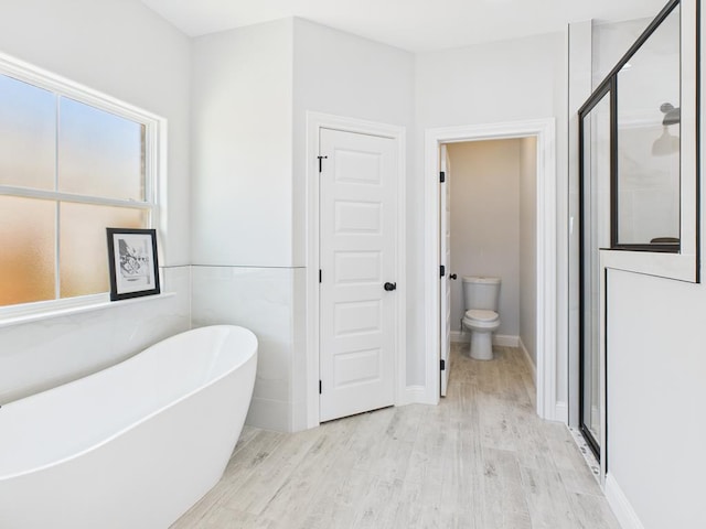 3725 Silver Spur Dr, San Angelo, TX 76904 - bathroom featuring a freestanding bath, wood finished floors, a stall shower, and toilet