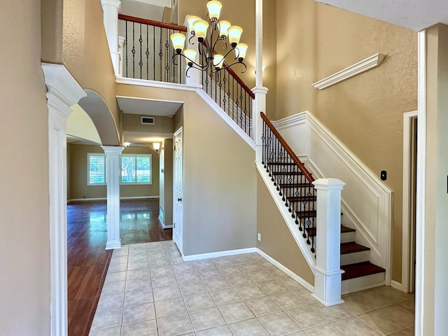 5202 Beverly Dr, San Angelo, TX 76904 - stairs featuring decorative columns, a chandelier, a towering ceiling, tile patterned floors, and arched walkways
