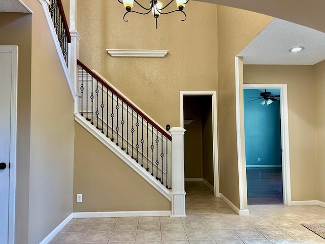 5202 Beverly Dr, San Angelo, TX 76904 - stairs featuring a ceiling fan, tile patterned floors, a chandelier, and baseboards