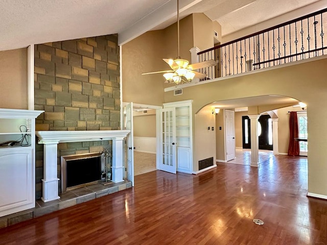 5202 Beverly Dr, San Angelo, TX 76904 - unfurnished living room featuring arched walkways, a ceiling fan, a stone fireplace, wood finished floors, and baseboards