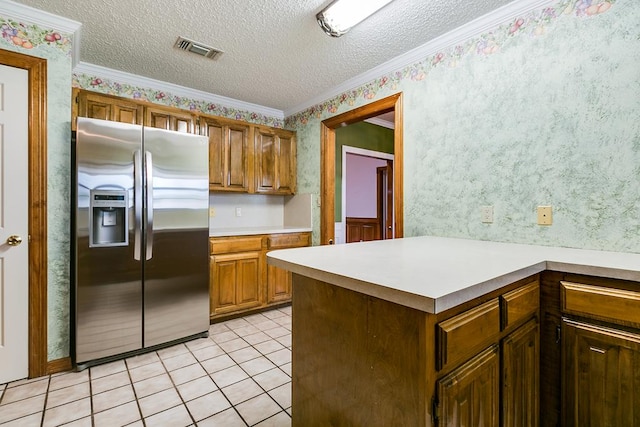  - kitchen with stainless steel fridge, wallpapered walls, light countertops, crown molding, and a textured ceiling