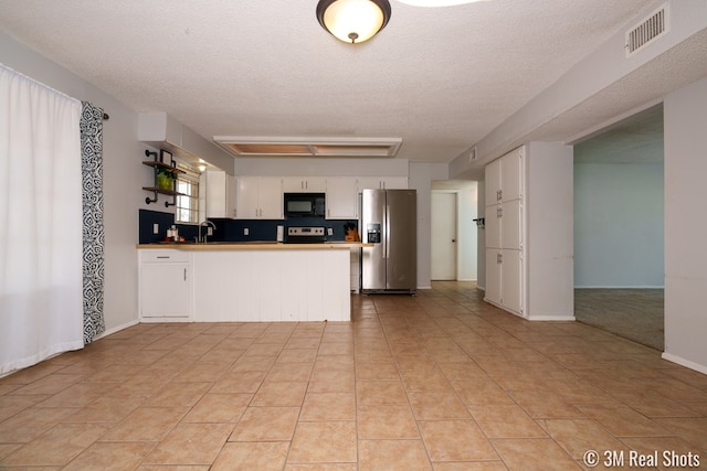 3317 Rockbrook Dr, San Angelo, TX 76904 - kitchen with stainless steel refrigerator with ice dispenser, black microwave, range with electric cooktop, a peninsula, and a textured ceiling