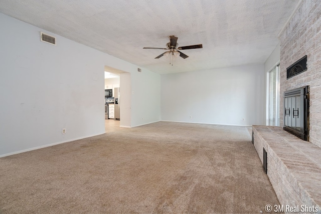 3317 Rockbrook Dr, San Angelo, TX 76904 - unfurnished living room with a fireplace, ceiling fan, light colored carpet, and a textured ceiling