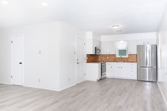 2007 Stanton St, Brady, TX 76825 - kitchen with appliances with stainless steel finishes, a sink, light wood-style floors, and white cabinetry