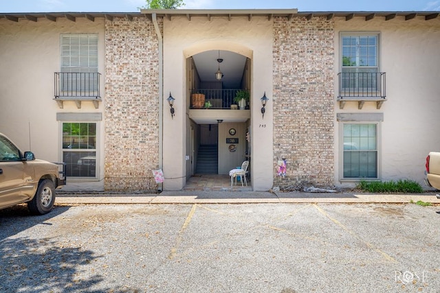view of exterior entry with stucco siding and uncovered parking