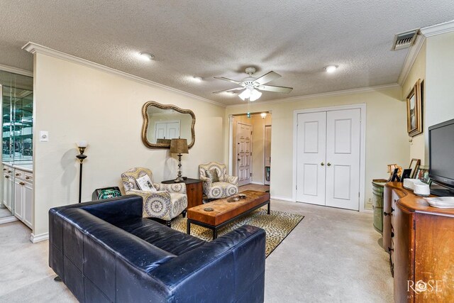 living room with ornamental molding, baseboards, light colored carpet, a textured ceiling, and a ceiling fan