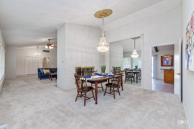 dining room featuring vaulted ceiling, a notable chandelier, a brick fireplace, light carpet, and a textured ceiling