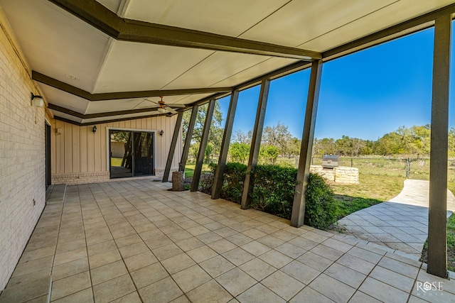 unfurnished sunroom featuring vaulted ceiling with beams and ceiling fan