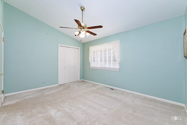 unfurnished bedroom featuring lofted ceiling, light colored carpet, ceiling fan, and a closet