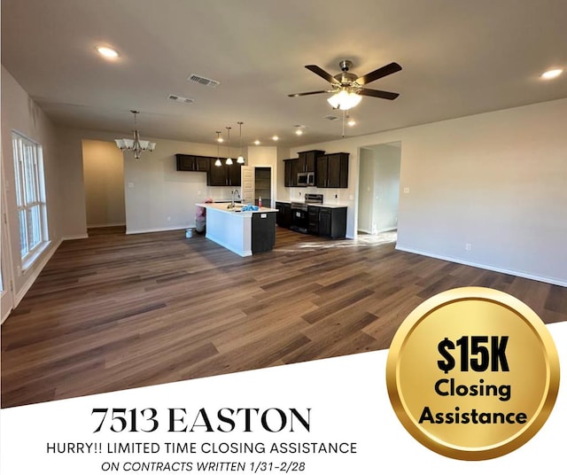 kitchen featuring ceiling fan with notable chandelier, dark hardwood / wood-style flooring, decorative light fixtures, and an island with sink