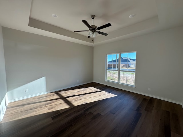 empty room featuring a tray ceiling, ceiling fan, and hardwood / wood-style flooring