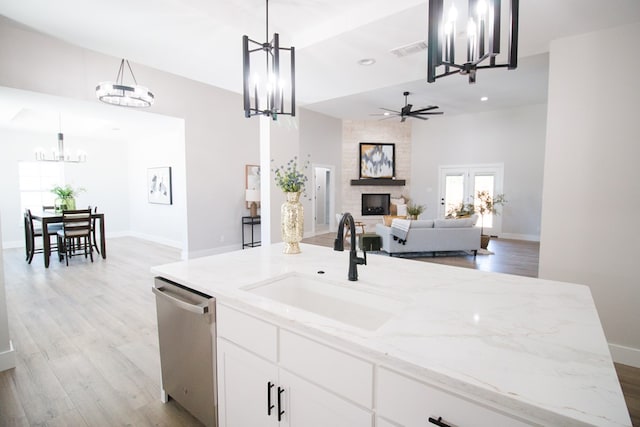 kitchen with sink, white cabinetry, light stone counters, dishwasher, and pendant lighting