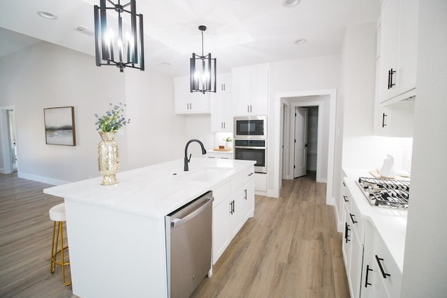 kitchen featuring sink, white cabinetry, appliances with stainless steel finishes, an island with sink, and pendant lighting