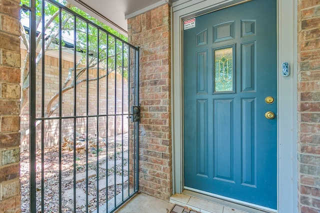 doorway to property with a gate and brick siding