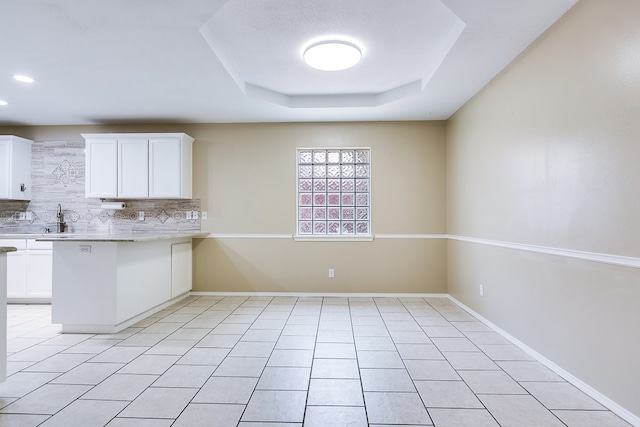 kitchen with light countertops, white cabinetry, a sink, and tasteful backsplash