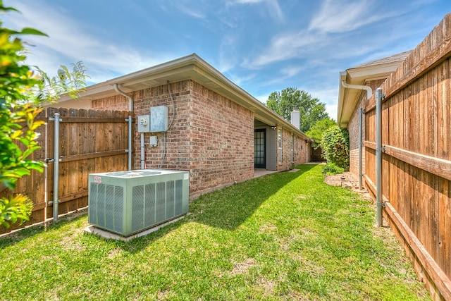 view of property exterior featuring central air condition unit, a lawn, a fenced backyard, and brick siding
