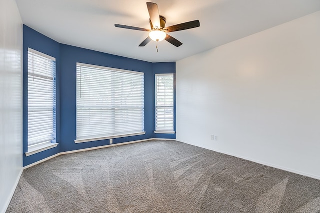 empty room featuring baseboards, carpet, a ceiling fan, and a wealth of natural light