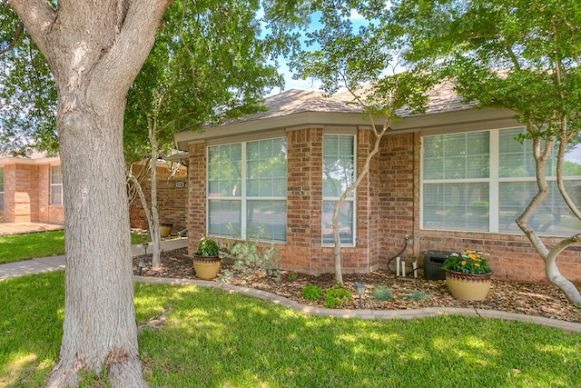view of side of home featuring a lawn and brick siding