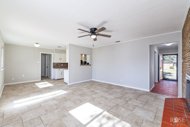 unfurnished living room with ceiling fan and a brick fireplace