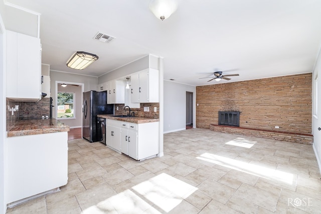 kitchen with white cabinets, a fireplace, sink, and backsplash