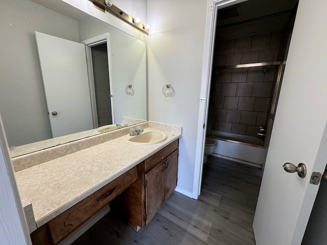 full bathroom with vanity, tiled shower / bath combo, wood-type flooring, and toilet