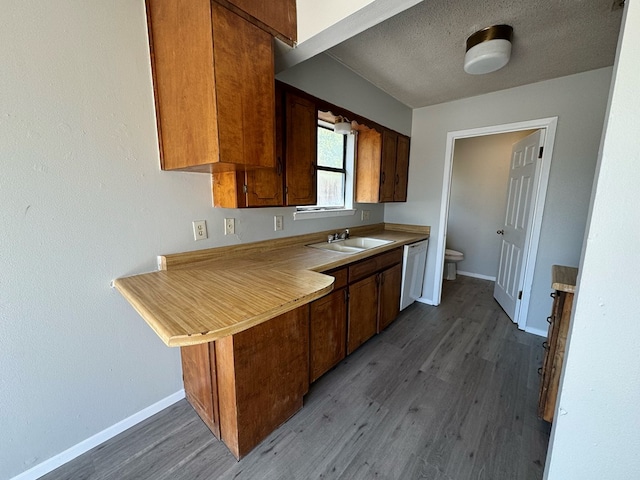 kitchen featuring sink, a textured ceiling, dishwasher, kitchen peninsula, and hardwood / wood-style floors