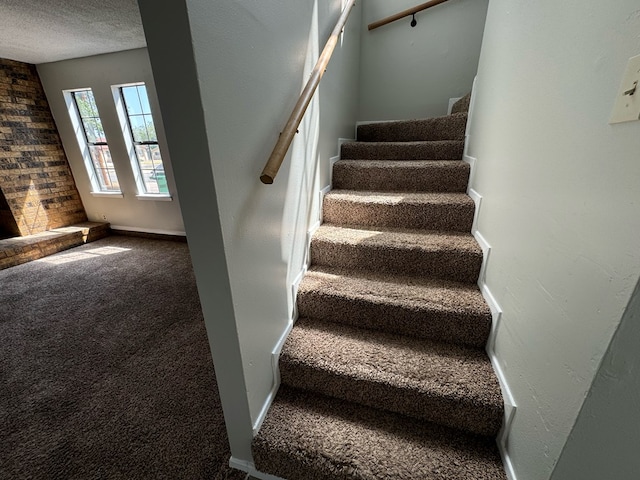 staircase featuring carpet floors and a textured ceiling